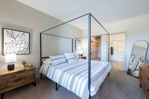 A bedroom with a four poster bed and a wooden nightstand.