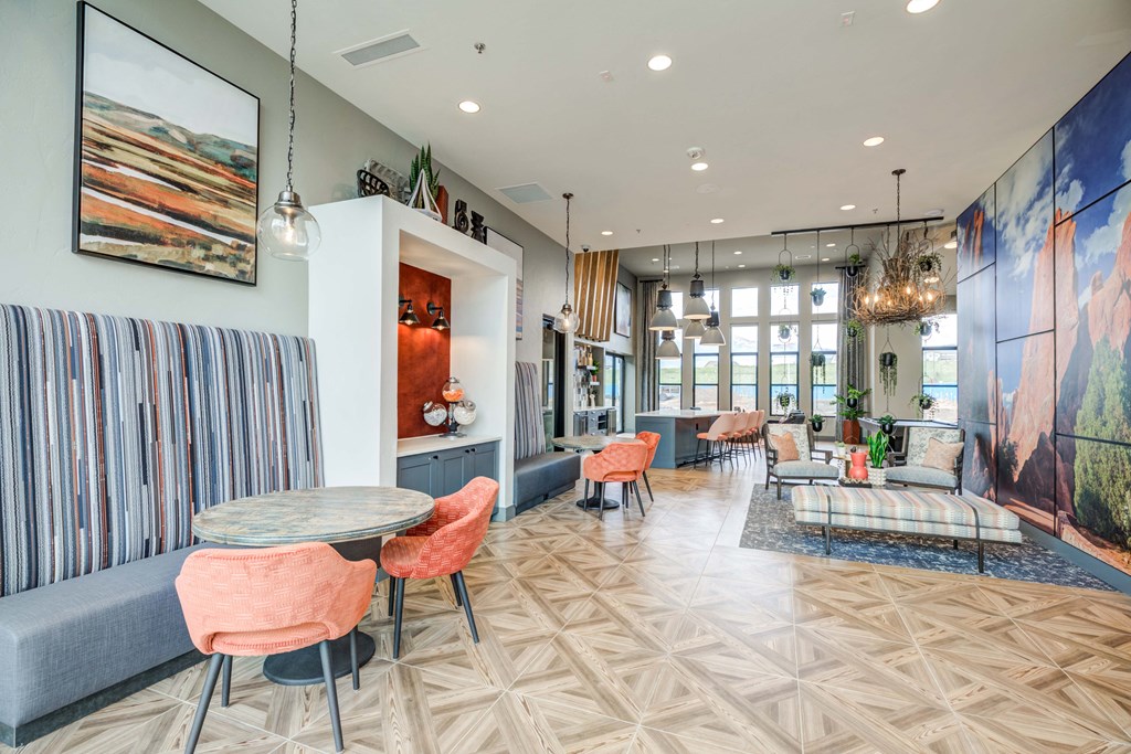 Community area with a couch, tables, and chairs and a large painting on the wall