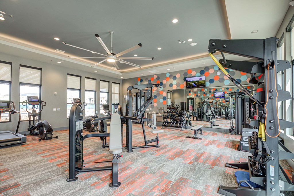 a spacious fitness room with cardio equipment and a flat screen tv