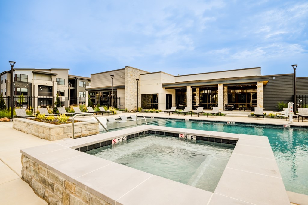 A swimming pool in front of a building with a stone wall.