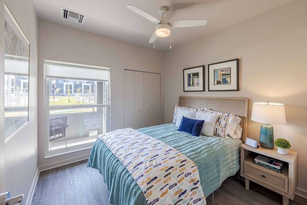 A bedroom with a bed, nightstand, and window.