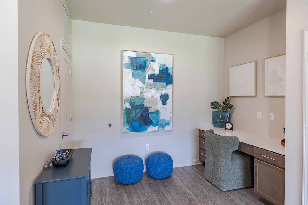 A room with a blue chair and a painting on the wall.