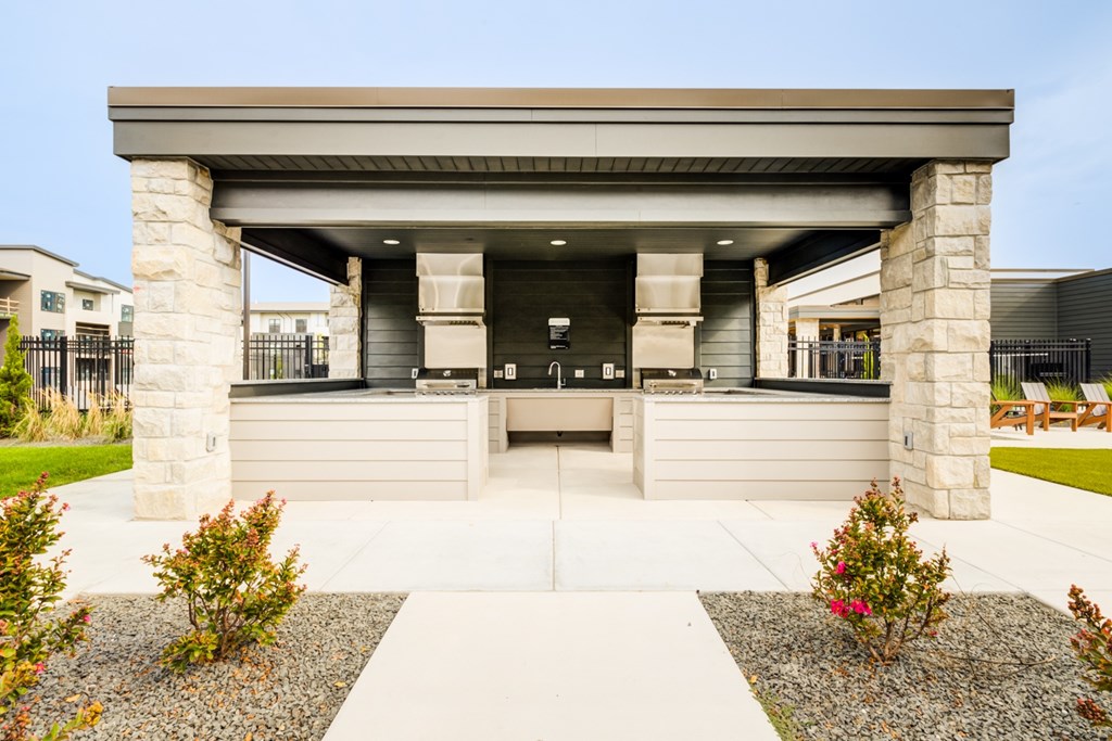 A modern house entrance with a stone pillar and a concrete walkway.