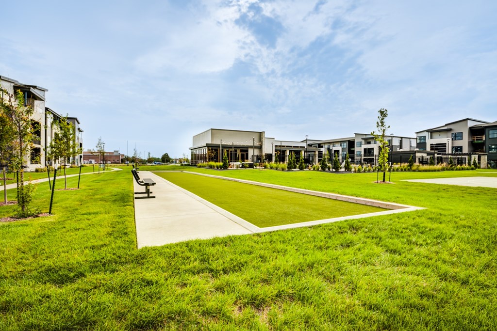 A park with a walking path and benches in front of a building.