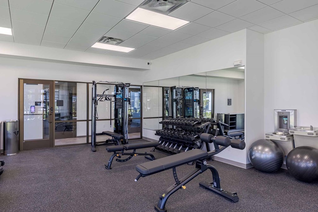 A gym with a variety of equipment including a leg press machine, a rowing machine, and a weight bench.