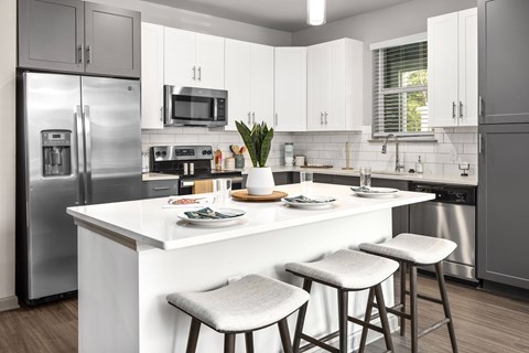 A modern kitchen with a white island and stools.