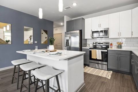 A modern kitchen with a white island and stools.