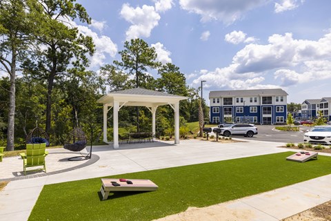 A white gazebo is surrounded by a grassy area and trees.