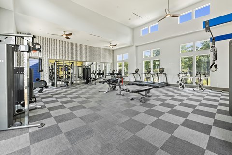A spacious gym with a variety of equipment and a checkered floor.