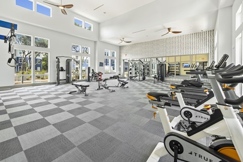 A gym with a checkered floor and a row of exercise bikes.