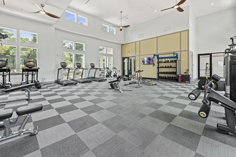 A spacious gym with a variety of exercise equipment and a checkered floor.