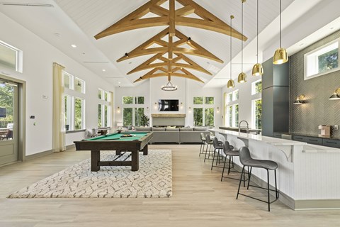 A billiard table is in the middle of a room with a bar and chairs.