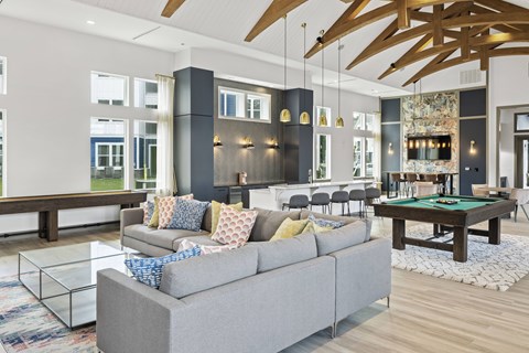 A living room with a grey couch and a pool table.