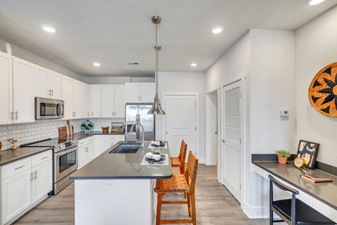 A kitchen with white cabinets and a black countertop.