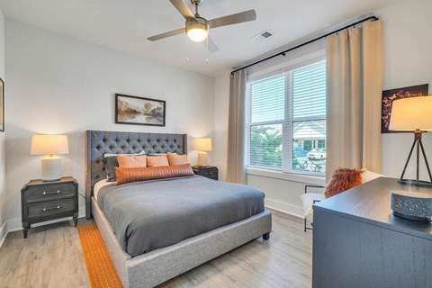 Modern bedroom with upholstered bed, ceiling fan and large windows