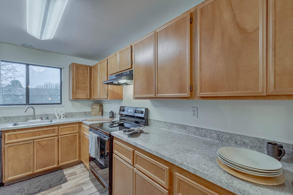 A kitchen with wooden cabinets and a stove top oven at Aspenridge Apartments, Vancouver, WA