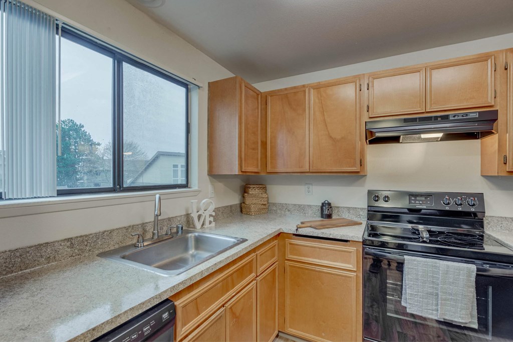 A kitchen with wooden cabinets and a black stove top oven. A kitchen with wooden cabinets and a black stove top oven at Aspenridge Apartments,Vancouver, WA