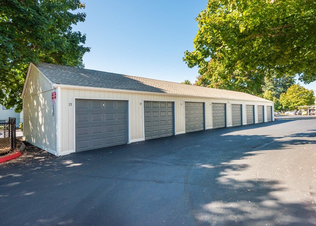 A long white building with a grey roof and a black fence at Aspenridge Apartments, WA 98683