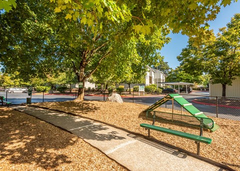 A playground with a green slide and a bench at Aspenridge Apartments, Vancouver, WA