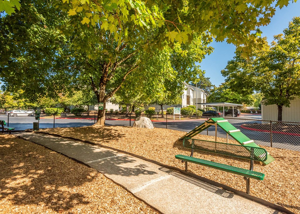 A playground with a green slide and a bench. A playground with a green slide and a bench at Aspenridge Apartments, Vancouver, WA
