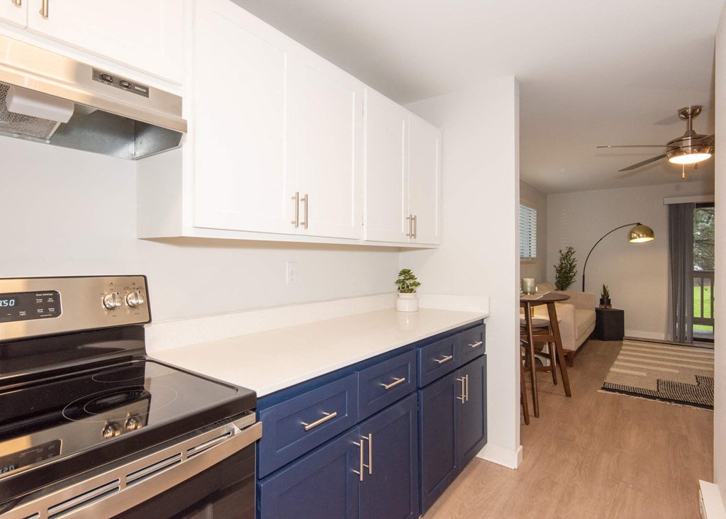 A kitchen with a stove top oven and blue cabinets at Aspenridge Apartments, Vancouver, WA