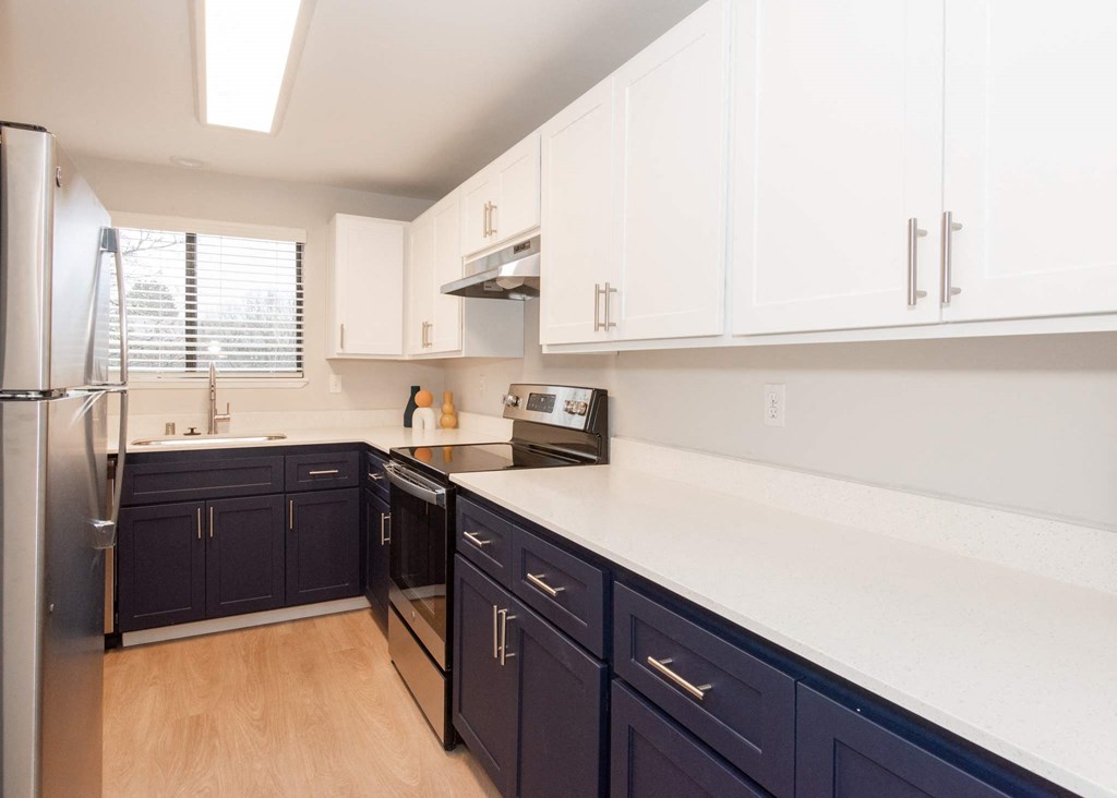 A kitchen with dark blue cabinets and white countertops at Aspenridge Apartments, WA 98683