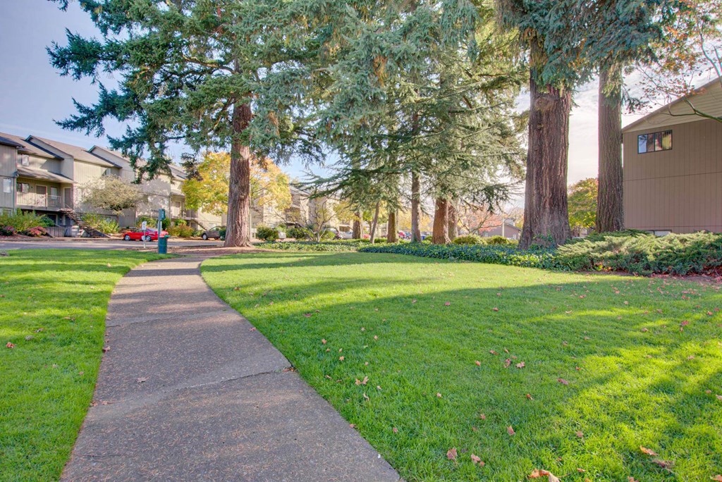 A walkway in a park with trees and grass at Aspenridge Apartments, Vancouver