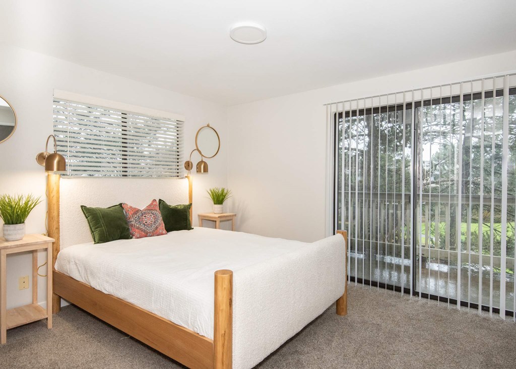 A bedroom with a bed, two lamps, and a window with blinds at Aspenridge Apartments, Vancouver, WA 98683