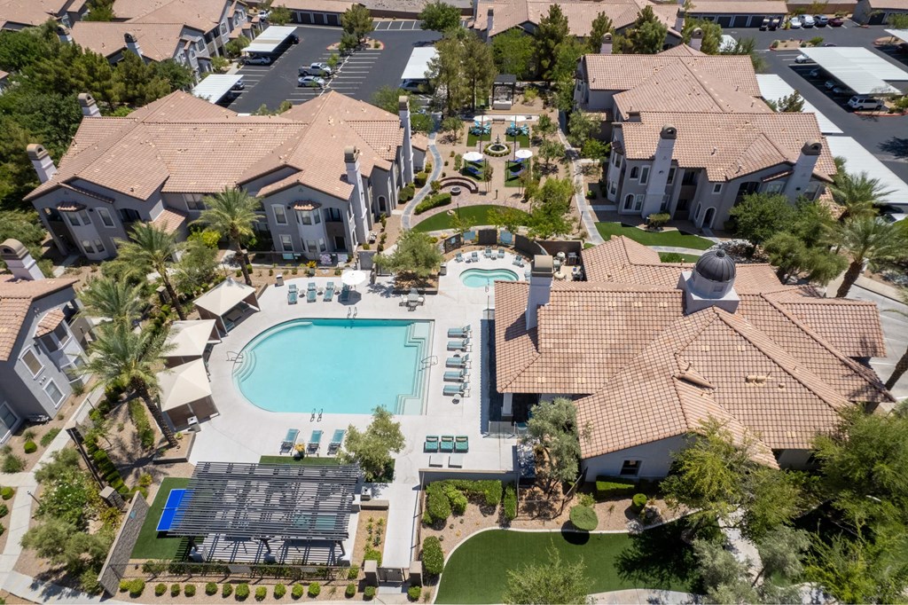 A large swimming pool surrounded by houses and palm trees.