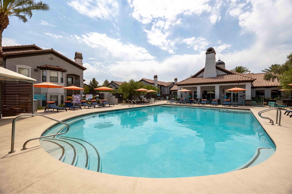 A large swimming pool in a resort with a building in the background.