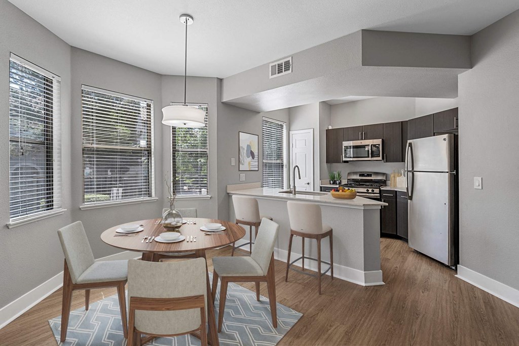 A modern kitchen with a dining table set for two.