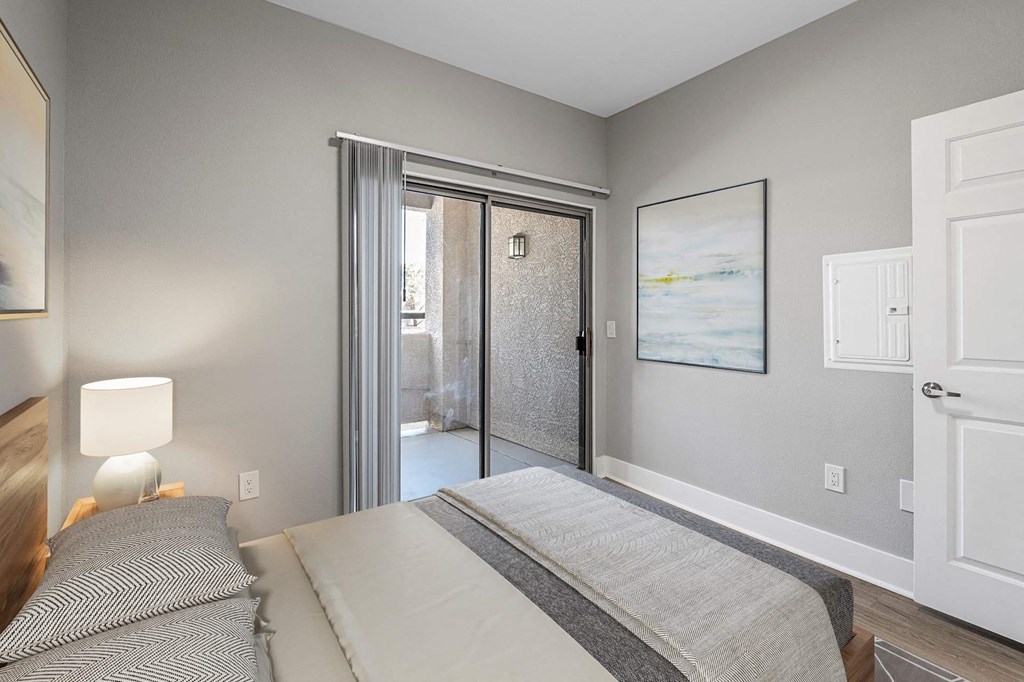 A bedroom with a bed, lamp, and painting.