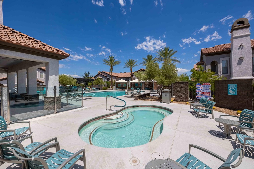 A pool with a slide and chairs around it.
