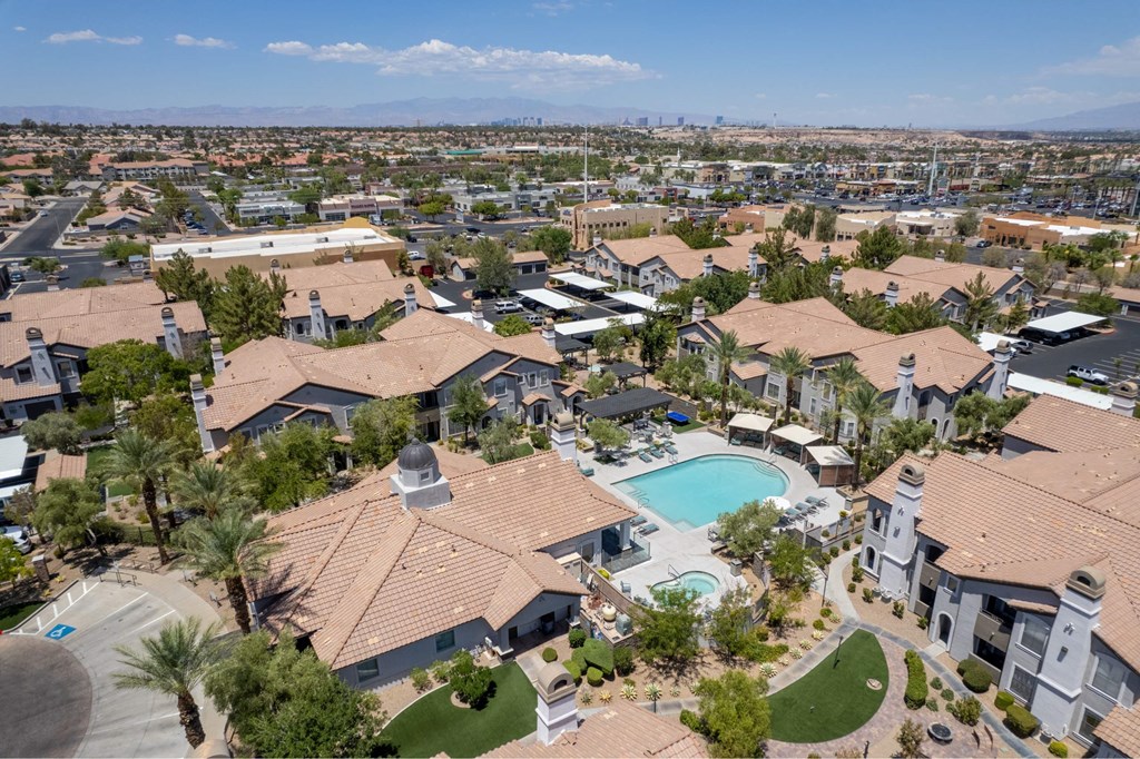 A large, well-maintained residential complex with a swimming pool and palm trees.