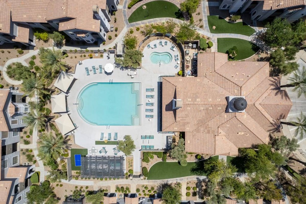 An aerial view of a resort with a swimming pool and palm trees.