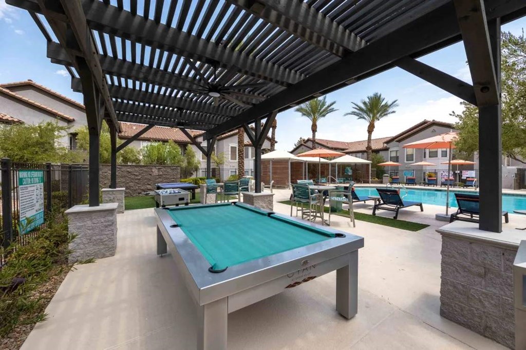 A pool table under a roof in a backyard.