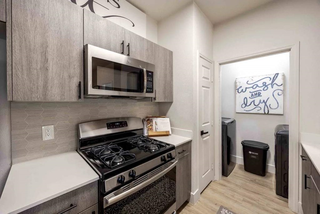 A kitchen with a black stove top oven and a microwave above it.