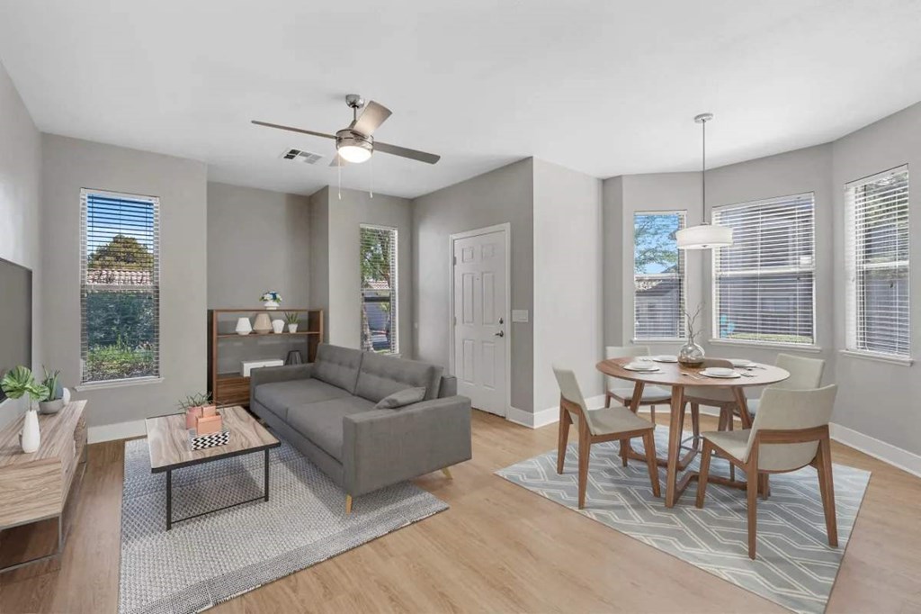 A living room with a grey couch, a coffee table, and a dining table with chairs.
