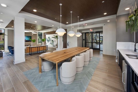A modern kitchen with a long wooden table and white chairs.
