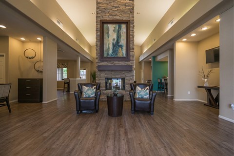 A living room with a stone fireplace and a painting above it.