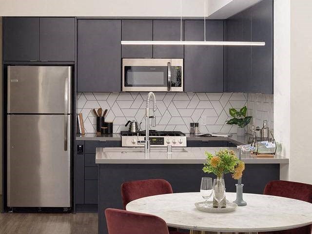 A modern kitchen with a stainless steel refrigerator and a white countertop.