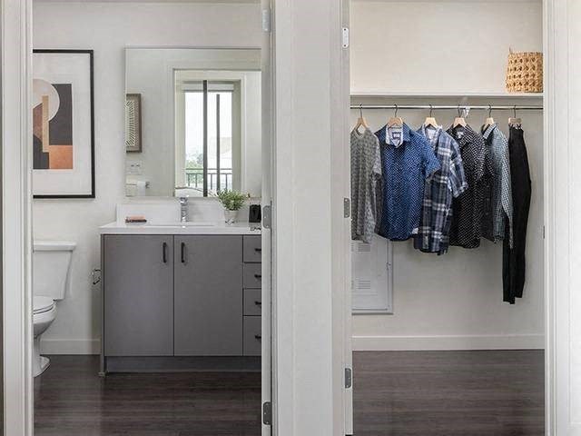 A bathroom with a grey cabinet and a mirror above it.