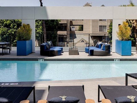 A pool with lounge chairs and a building in the background.