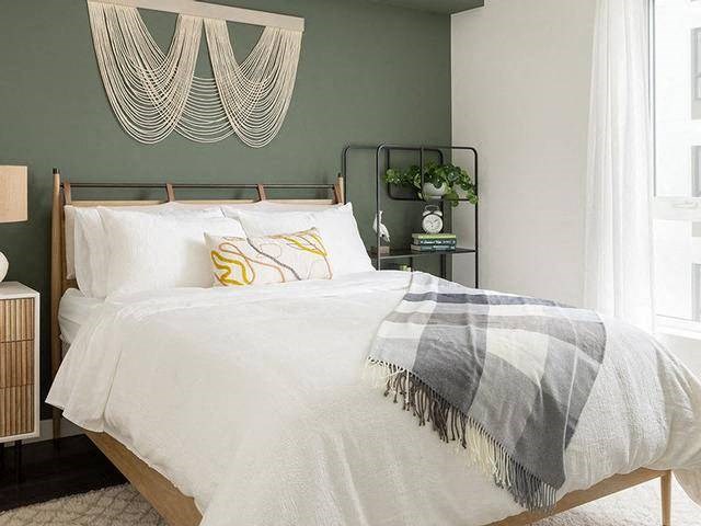 A bed with a white comforter and a grey throw is in the image.