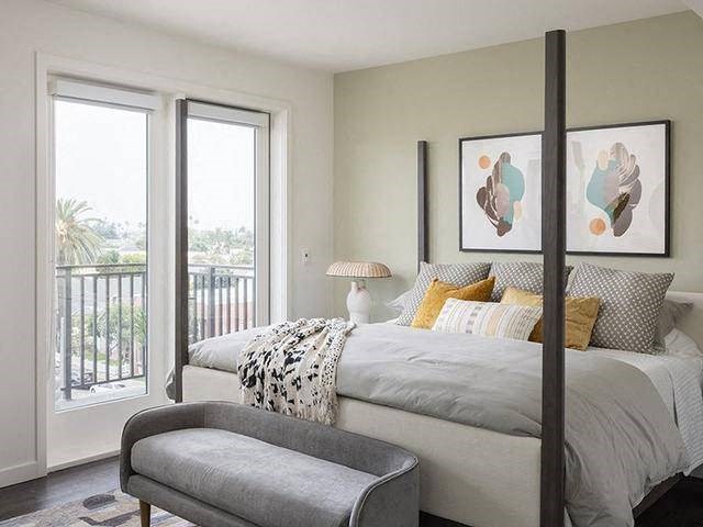 A bedroom with a large bed and a balcony with a view of the outside.