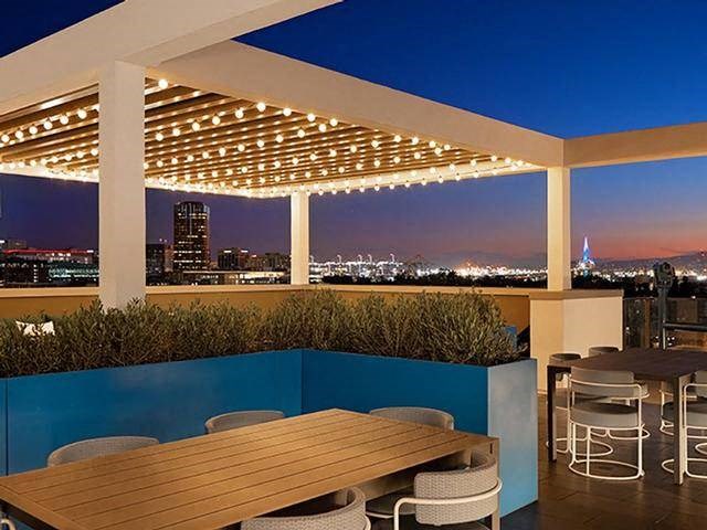 A rooftop patio with a table and chairs overlooking a city skyline at dusk.