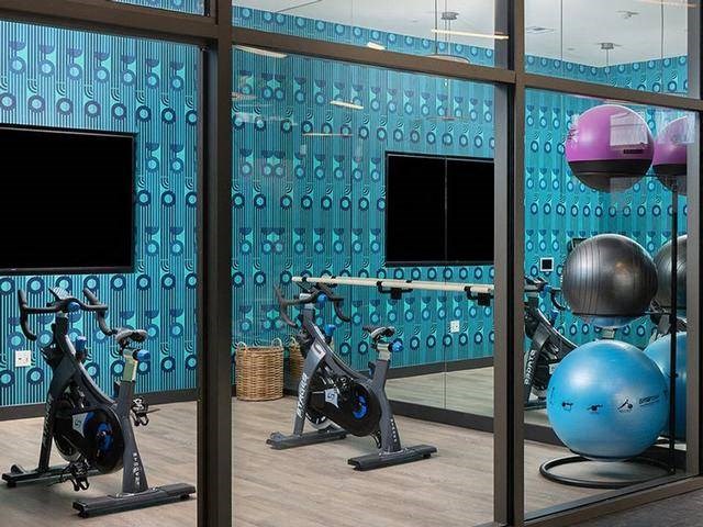 A gym with exercise equipment and a mirrored wall.