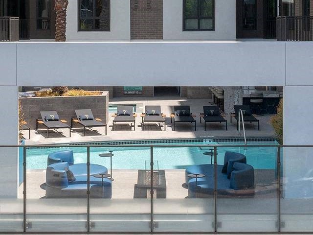 A pool with lounge chairs and umbrellas is seen from a balcony.