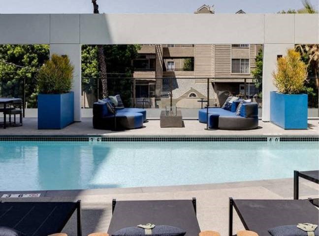 A poolside area with lounge chairs and a building in the background.