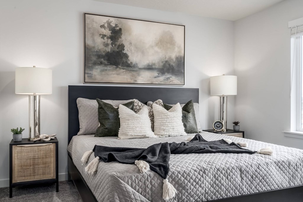 A bedroom with a large bed and a painting above it.